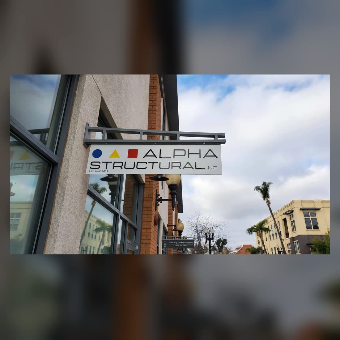 Real projecting Alpha Structural blade sign mounted above a sidewalk