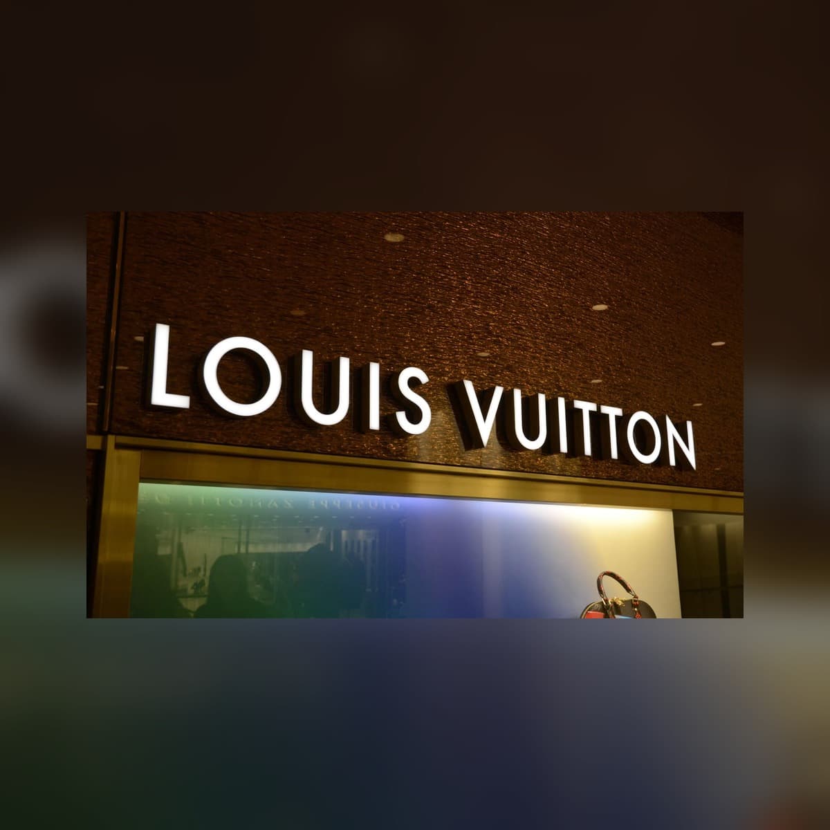 Real frontlit Moslors storefront sign on a glass retail building